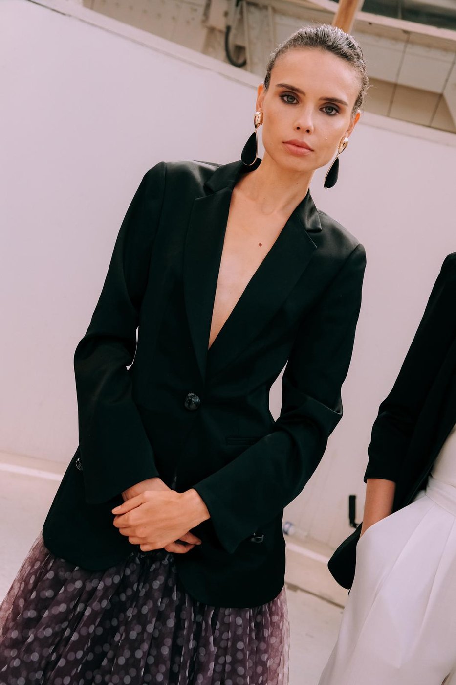 Portrait de mannequin en blazer noir, smoky léger et boucles d'oreilles dorées