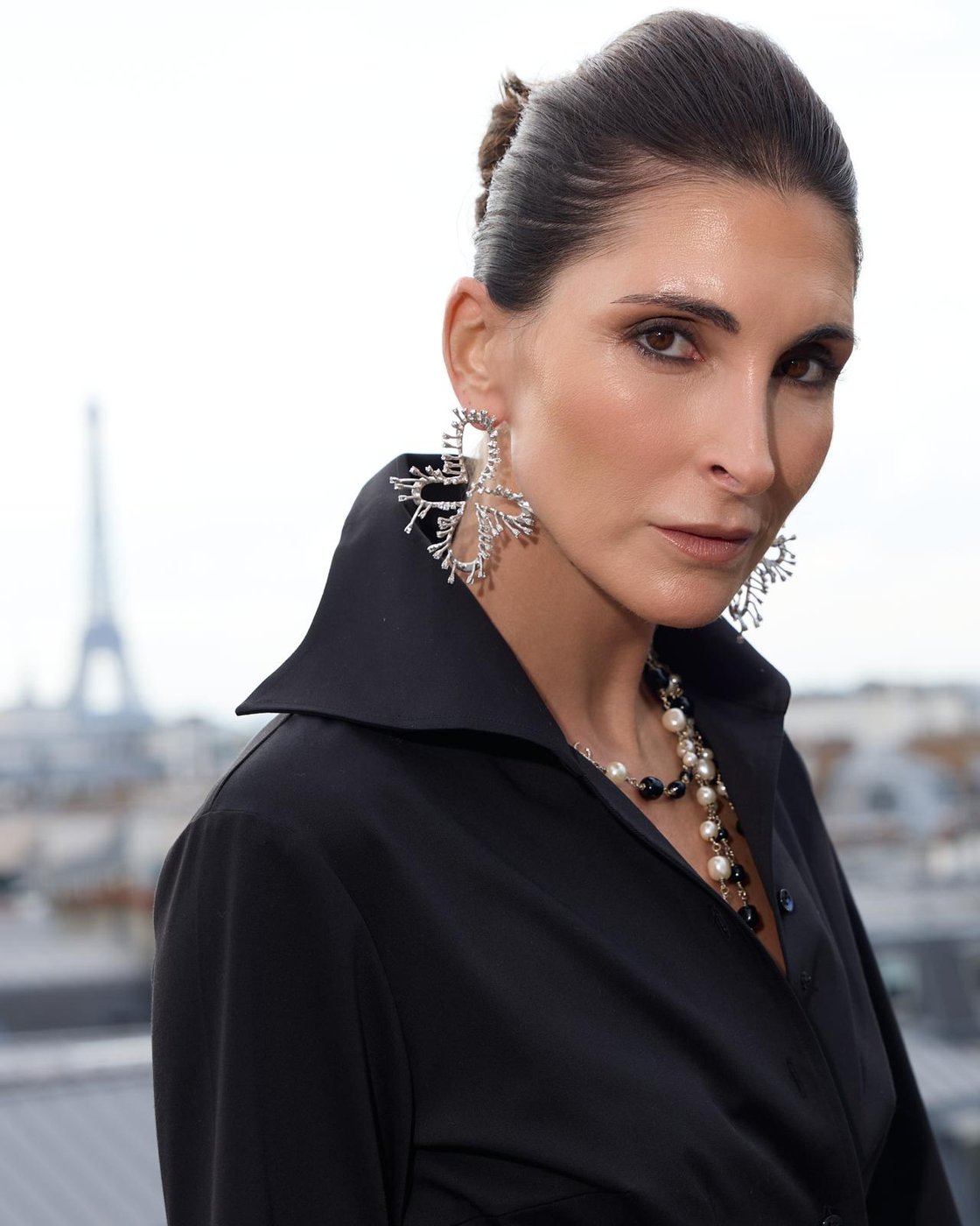 Portrait maquillage naturel lumineux et chignon lissé, boucles d'oreilles bijoux, tour Eiffel en fond